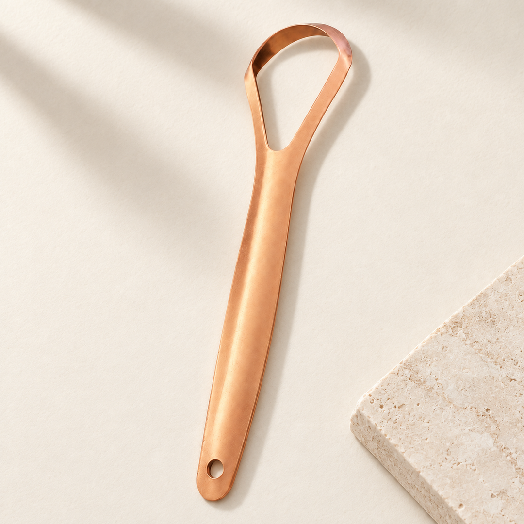 The whole scraper on a cream surface beside a stone tile, handle tapering to a hanging hole