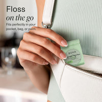 Dispenser being slipped into the front pocket of a crossbody bag