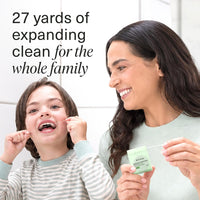 Parent and child flossing together, the parent holding the green dispenser